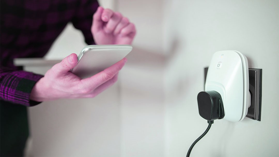 enchufes-inteligentes-hogar uno de los enchufes inteligentes blanco controlado por una persona con smartphone
