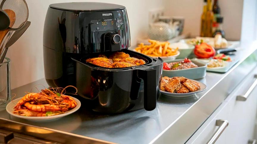 freidora de aire philips en color negro junto algunos platos preparados