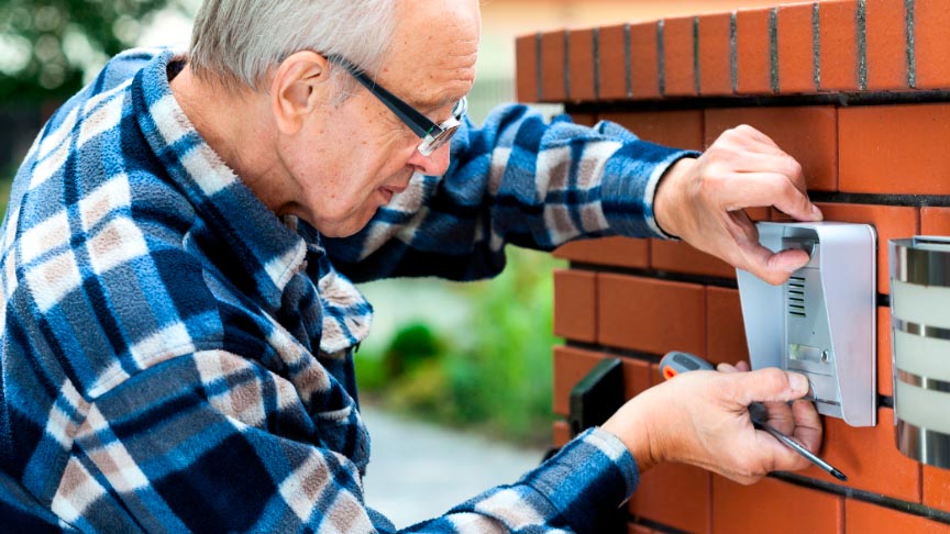 instalacion-videoporteros hombre de edad avanzada realizando la instalación de un videoportero